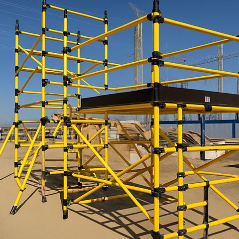 Yellow scaffolding structure with safety rails on a construction site.