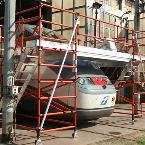 High-speed train undergoing maintenance inside a facility with scaffolding around it.