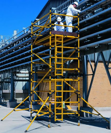 Workers on yellow scaffolding performing maintenance on large industrial pipes.