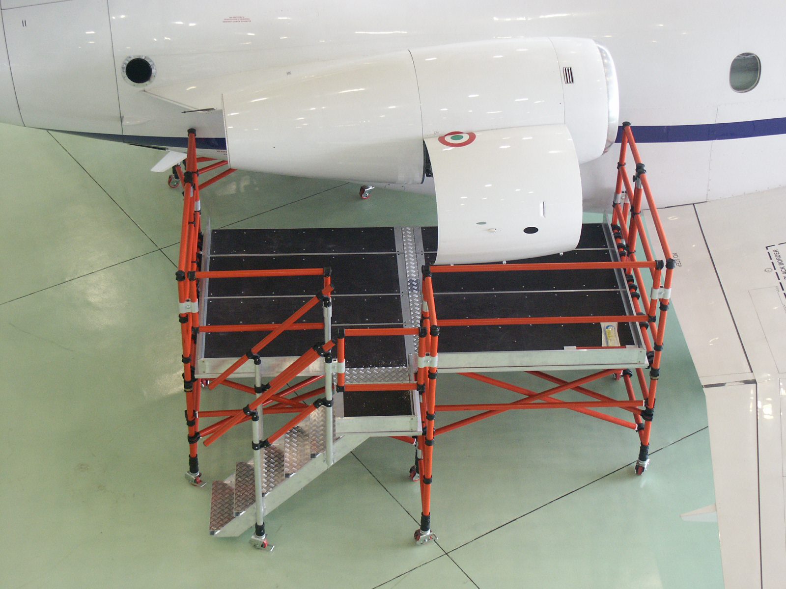 Aircraft wing section supported by scaffolding inside a hangar.