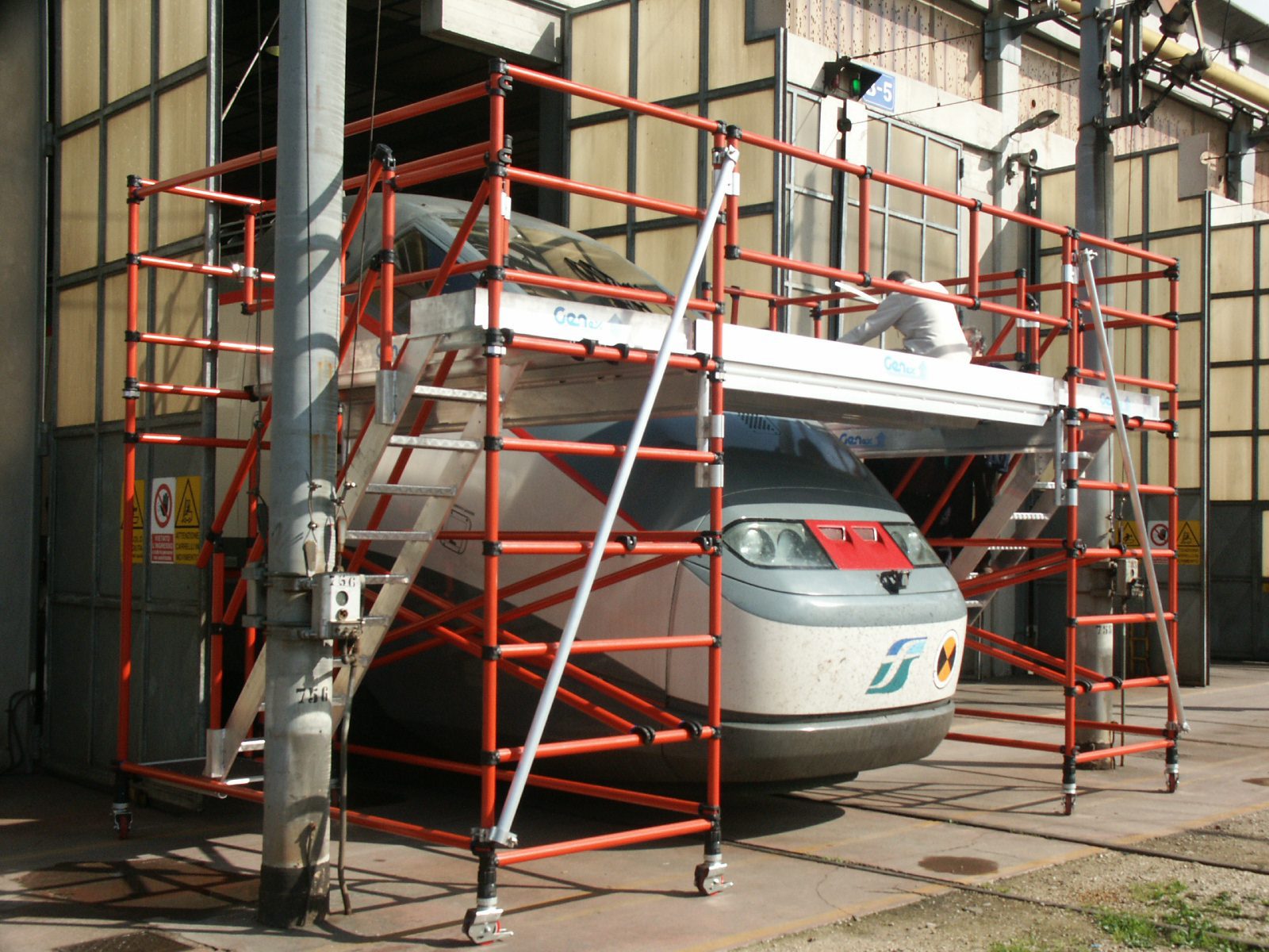 A red scaffold structure surrounds a suspended white gondola lift cabin.